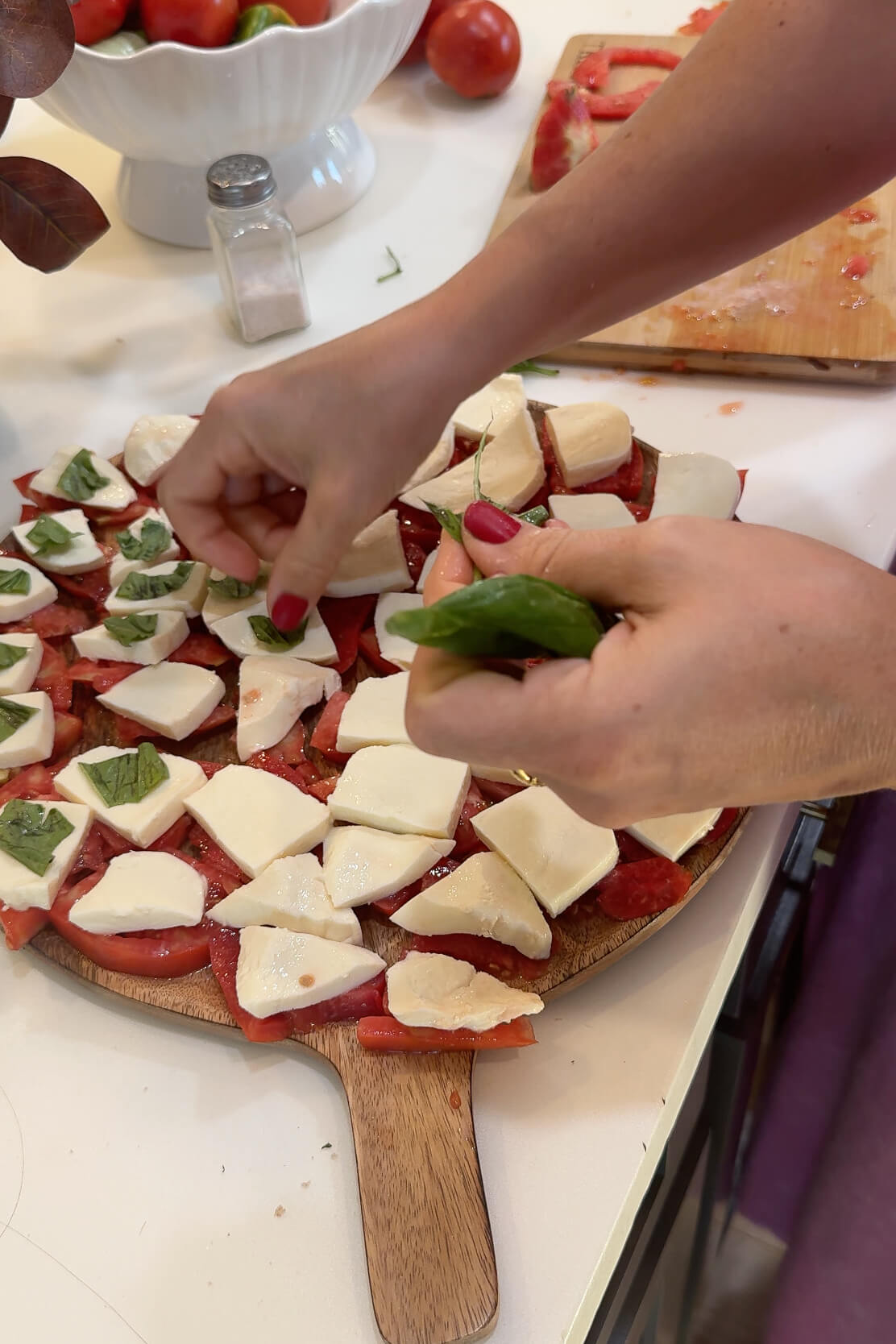 Assembling a caprese salad on a platter.